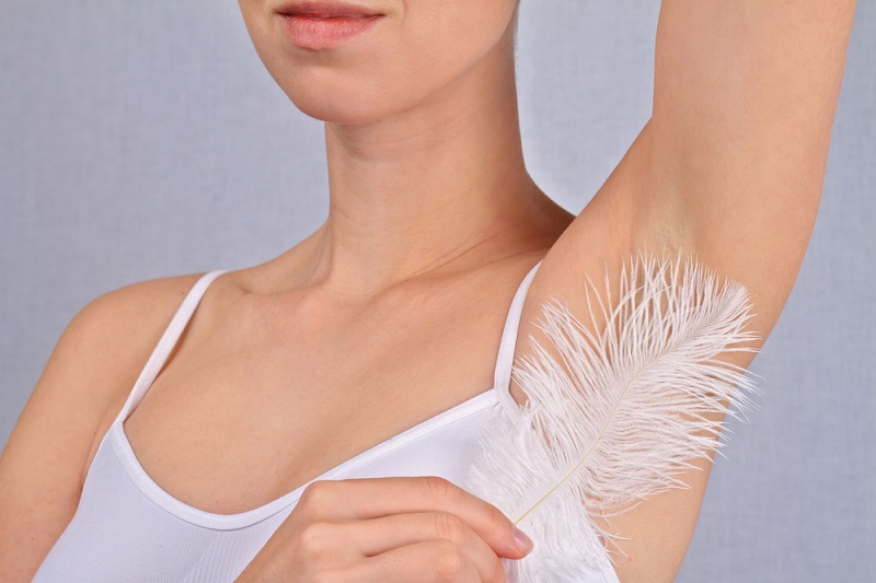 Woman runs a feather on skin