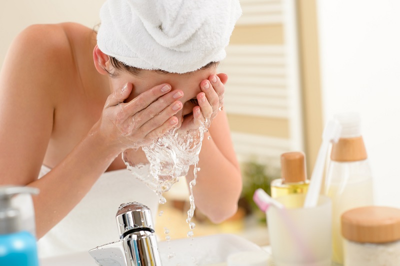 Woman splashing face with water in bathroom
